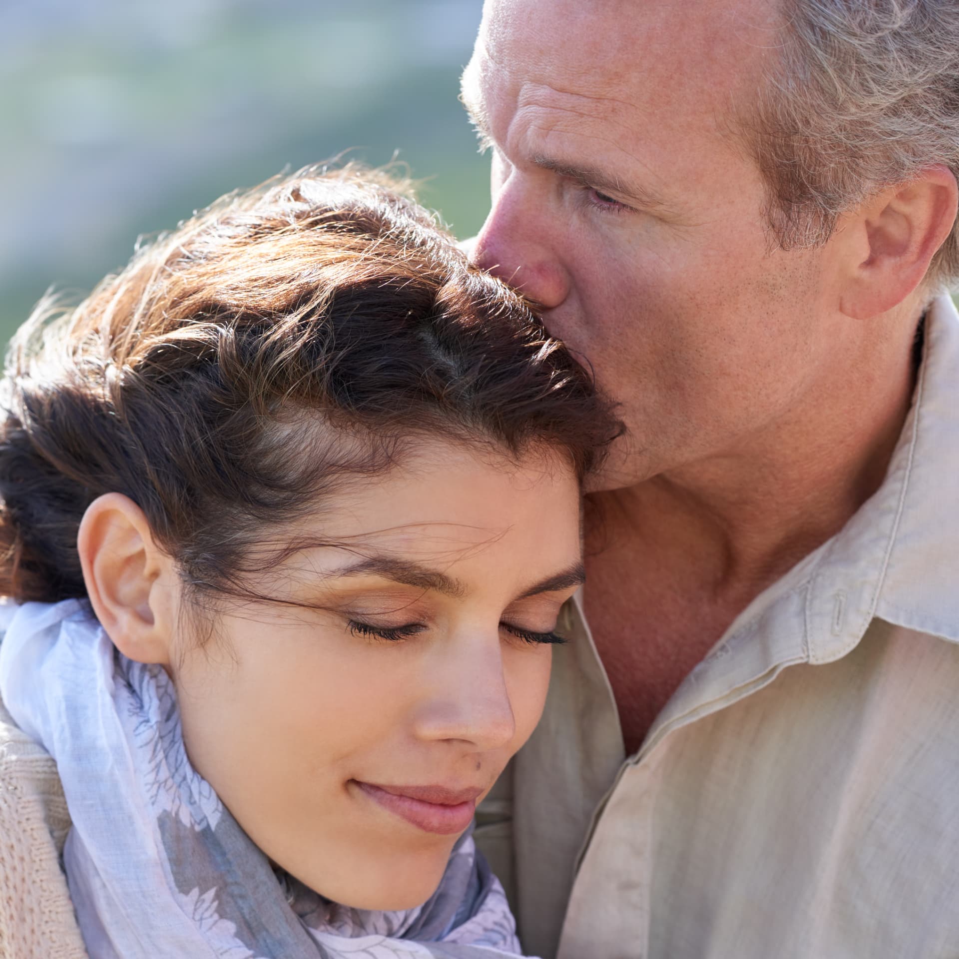 Homem beijando a testa de uma mulher em um momento de carinho