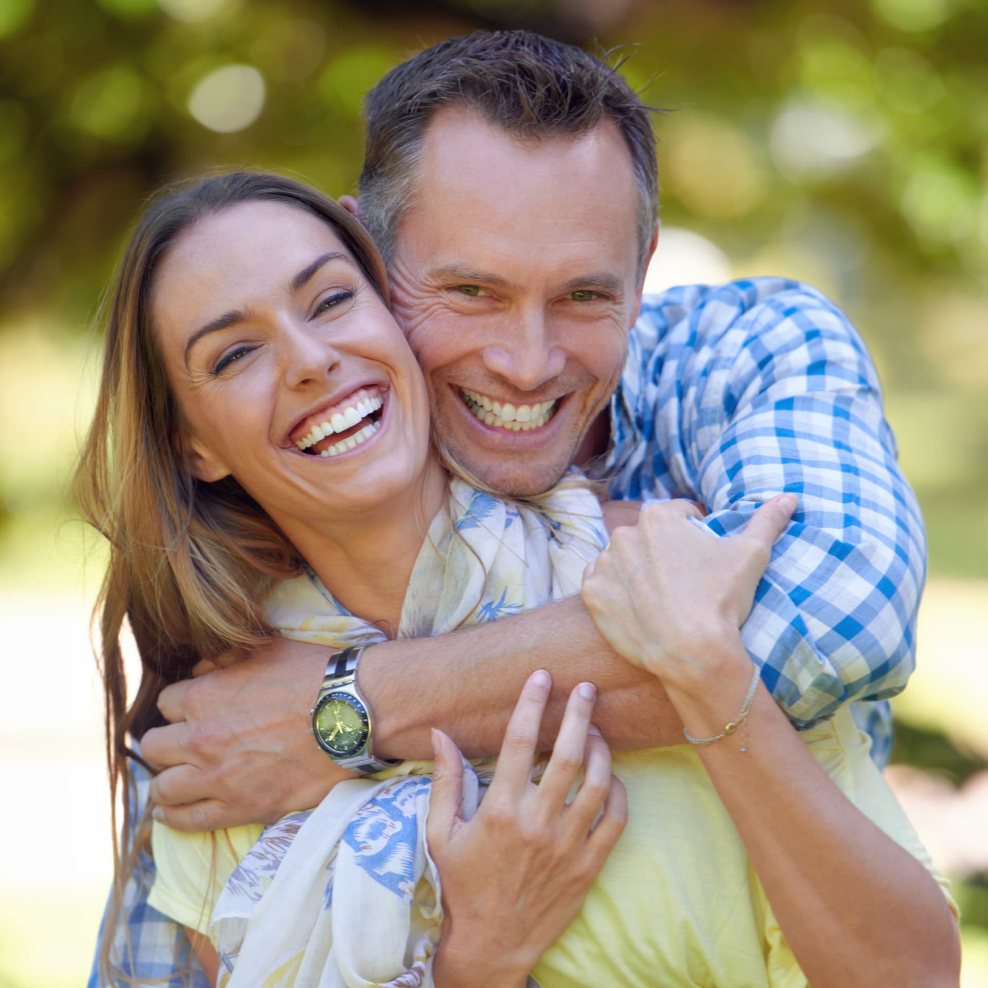 Casal sorrindo e abraçado em um jardim verde