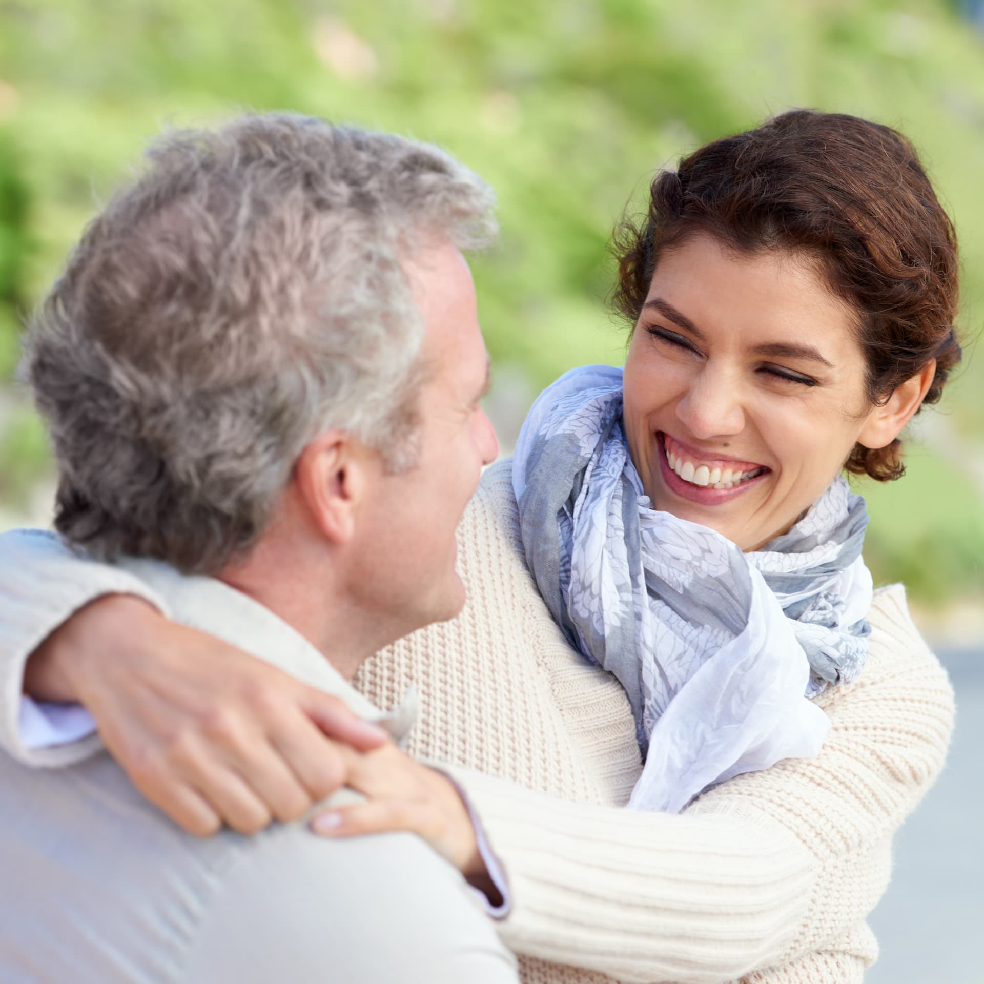 Mulher sorrindo enquanto abraça um homem ao ar livre
